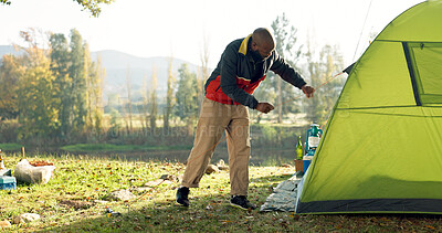 Camping, tent and black man setup in nature for shelter on outdoor holiday, vacation and adventure, Campsite, traveling and male person with hammer for pins for gear in woods, forest and countryside