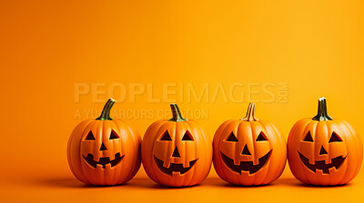 Row of carved halloween pumpkins on orange copyspace background.