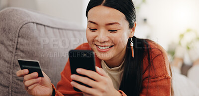 Asian woman, credit card and phone relaxing on her sofa online shopping, ecommerce and fintech easy payment. Young person in China typing bank information on cellphone for finance transaction at home