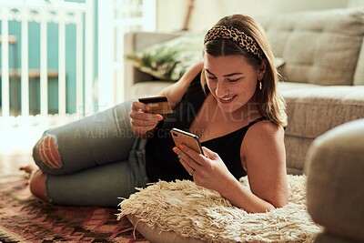 Buy stock photo Shot of a young woman using a smartphone and credit card in her living room at home