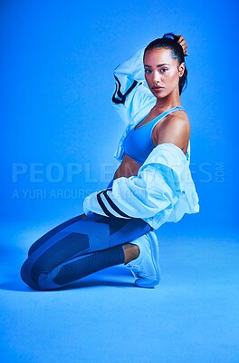 Buy stock photo Full length portrait of an attractive young female athlete posing on her knees against a blue background