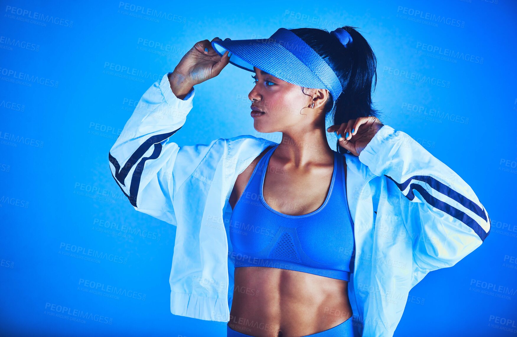 Buy stock photo Cropped shot of an attractive young female athlete posing against a blue background