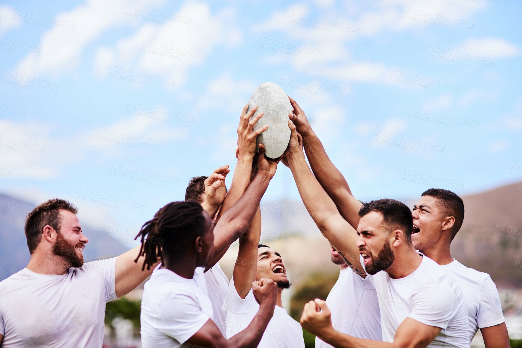 Buy stock photo Shot of a group of young rugby players raising a rugby ball in solidarity at a game