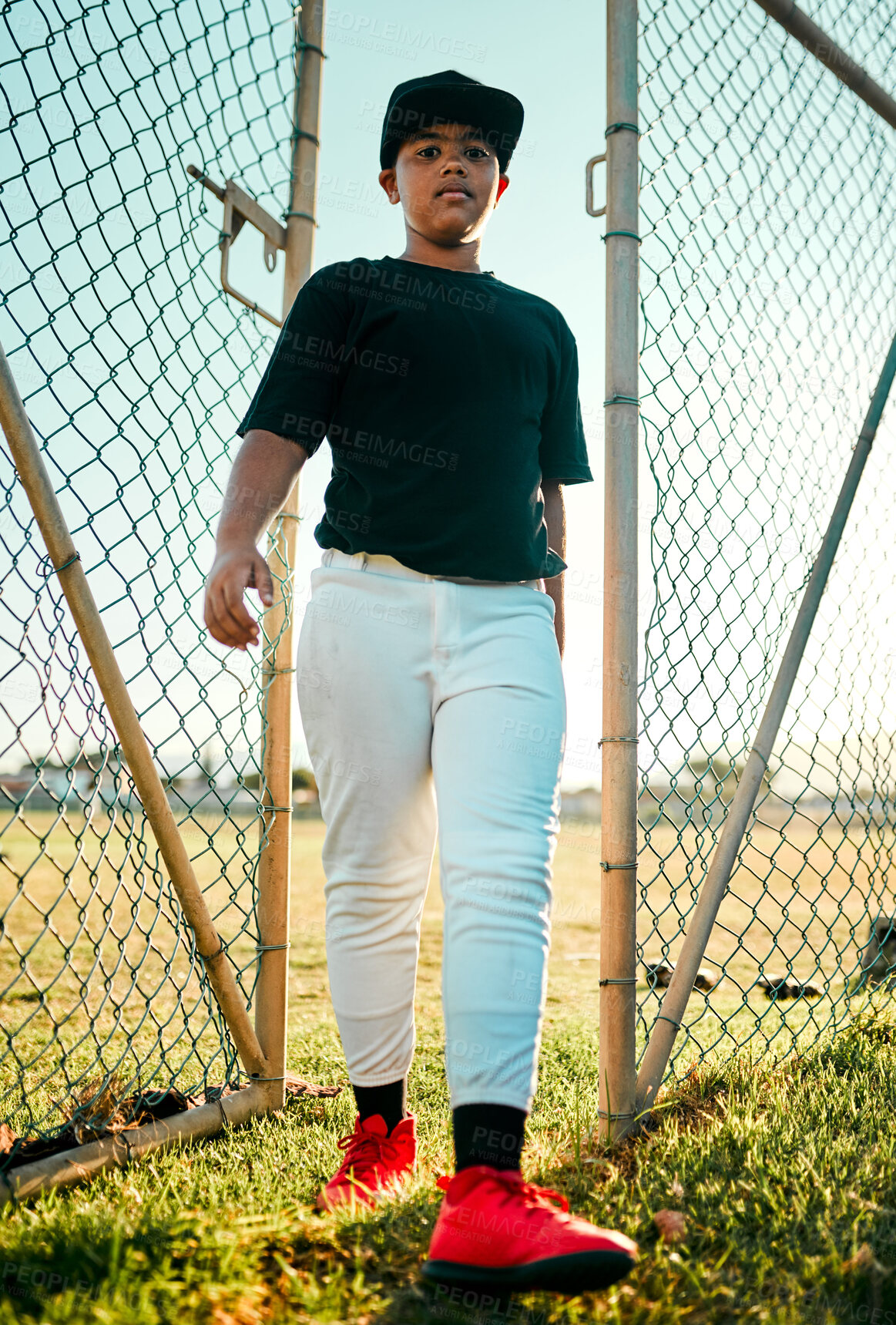 Buy stock photo Shot of a young baseball player walking through a gate