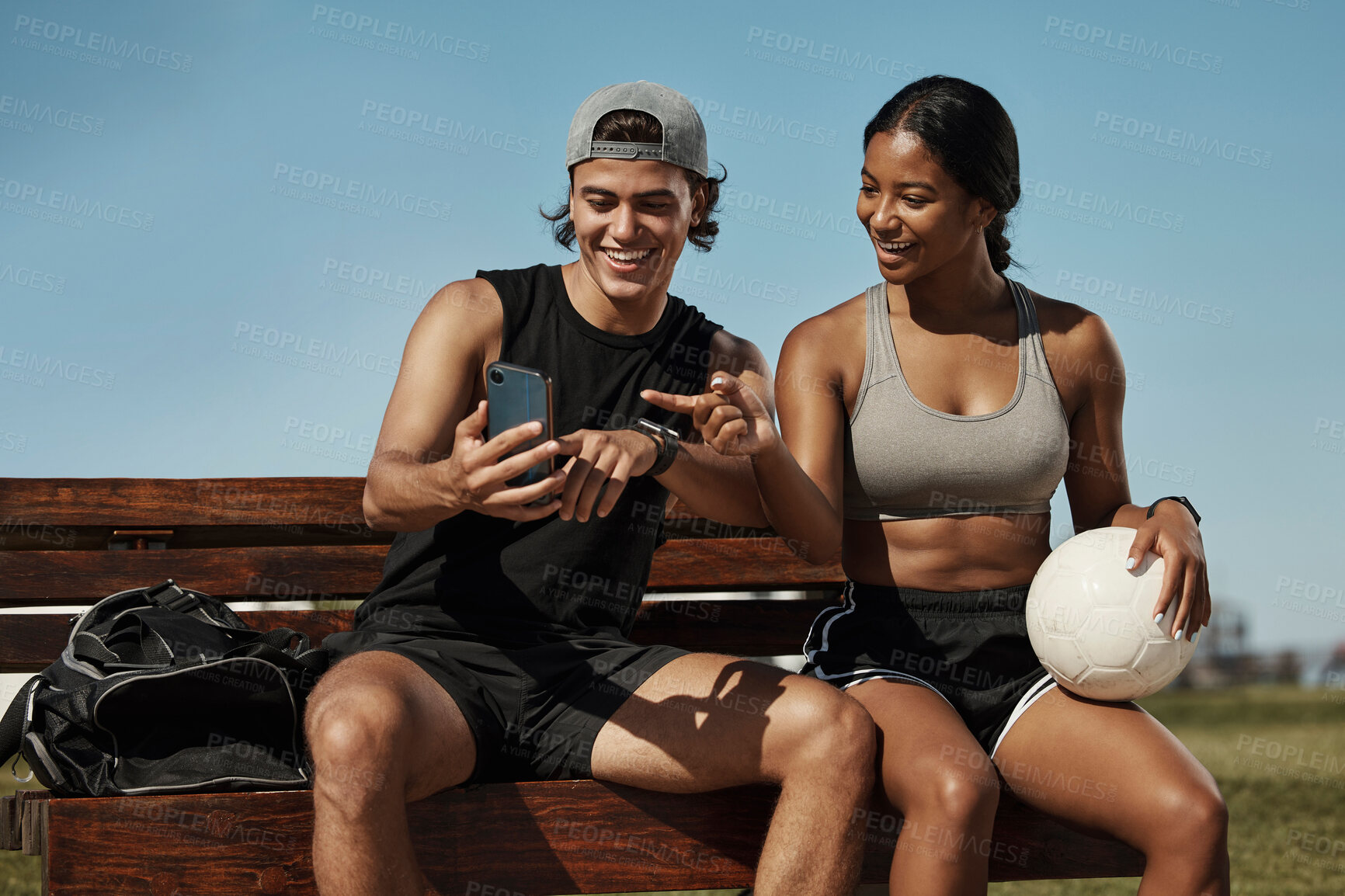 Buy stock photo Sports friends, phone and relax while sitting in a park together, bond and laughing at social media post before morning cardio. Fitness, couple and online entertainment on park bench after training 