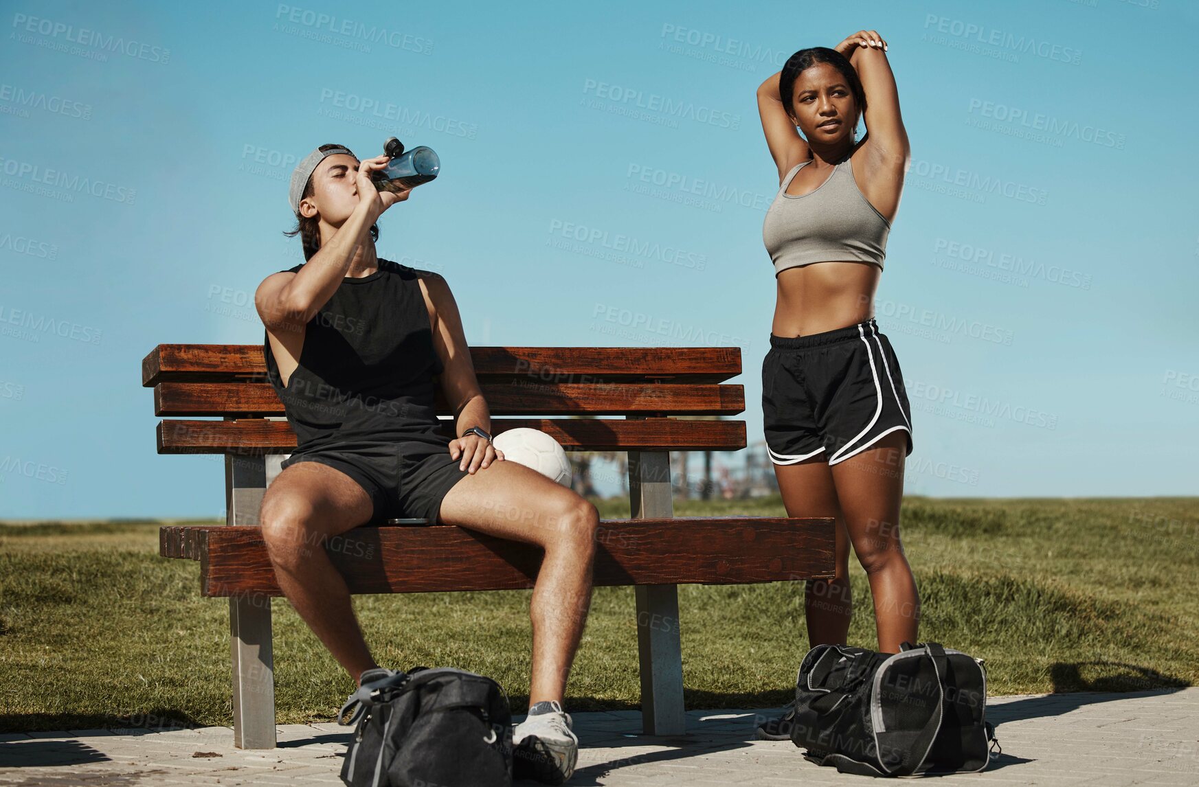 Buy stock photo Man, woman and fitness break for stretching, drinking water or muscle recovery after training, exercise and workout. Soccer players, sports friends or football players in warmup in nature garden park