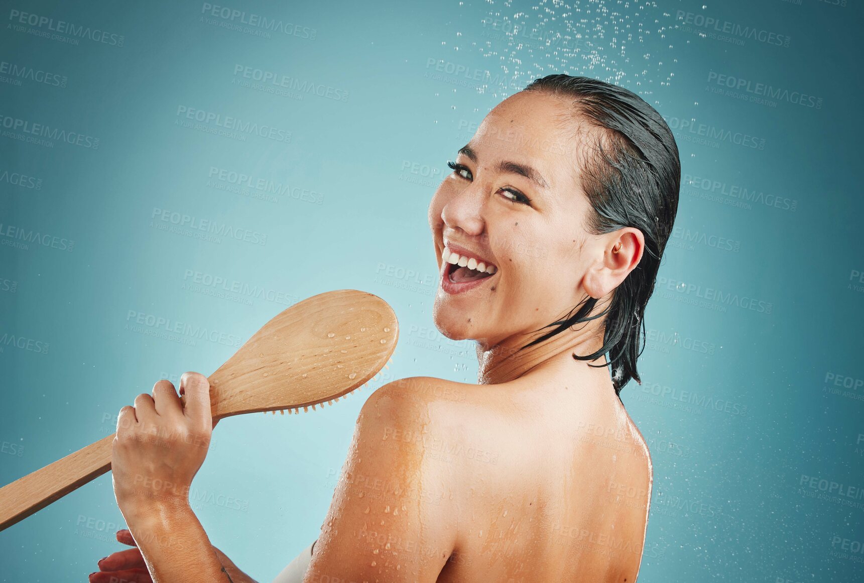 Buy stock photo Woman, singing and shower in studio for wellness, skin and body care on a blue background, happy and relax. Singer, bathroom and water splash karaoke by portrait of asian girl having fun and grooming