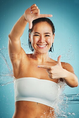 Buy stock photo Shower, water and hands with a woman in studio on a blue background for hygiene or hydration. Frame, cleaning and bathroom with a female washing or cleansing with hand sign for hygienic body care