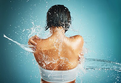 Buy stock photo Water splash, shower and woman in studio for wellness, cleaning and body, grooming and back on blue background. Beauty splash, hair and girl model in water for washing, skincare and beauty hygiene