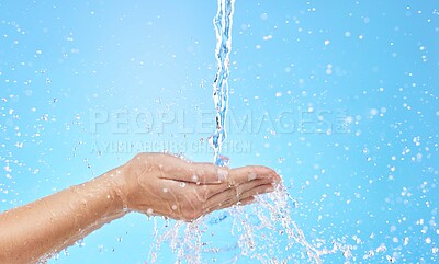 Buy stock photo Hand, water and cleaning with a splash in studio on a blue background for hygiene or hydration. Mockup, health and wellness with a female washing under a water splash in the bathroom for skincare