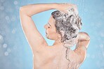 Woman, skincare and hair care beauty in shower from back on blue background, shampoo and hygiene routine in morning. Healthy model in water cleaning hair with running water for clean fresh lifestyle
