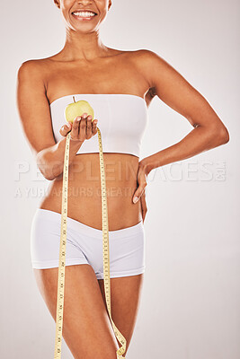 Buy stock photo Lose weight, tape measure and body with black woman and apple for nutrition and diet with fitness isolated on studio background. Health, smile and healthy lifestyle with weightloss and clean eating 