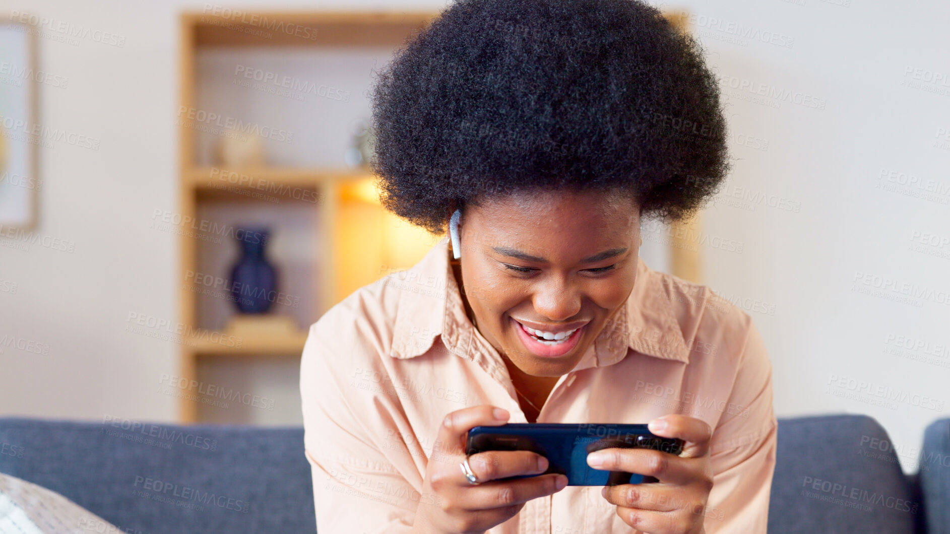 Buy stock photo Face, phone and gamer with a black woman on a sofa in the living room of her home closeup for entertainment. Smile, mobile app and a happy young girl gaming or playing an online video game in a house