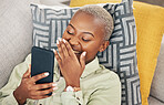 Black woman on sofa with phone, laughing and meme on social media, message or video online. Happy face, smile and internet, girl on couch with digital app on smartphone and funny viral post in home.