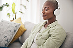 Black woman, listening and meditation podcast on headphones in home, living room or peace on sofa in lounge. Music, tech and happiness on face of person with calm, mindset and wellness in apartment