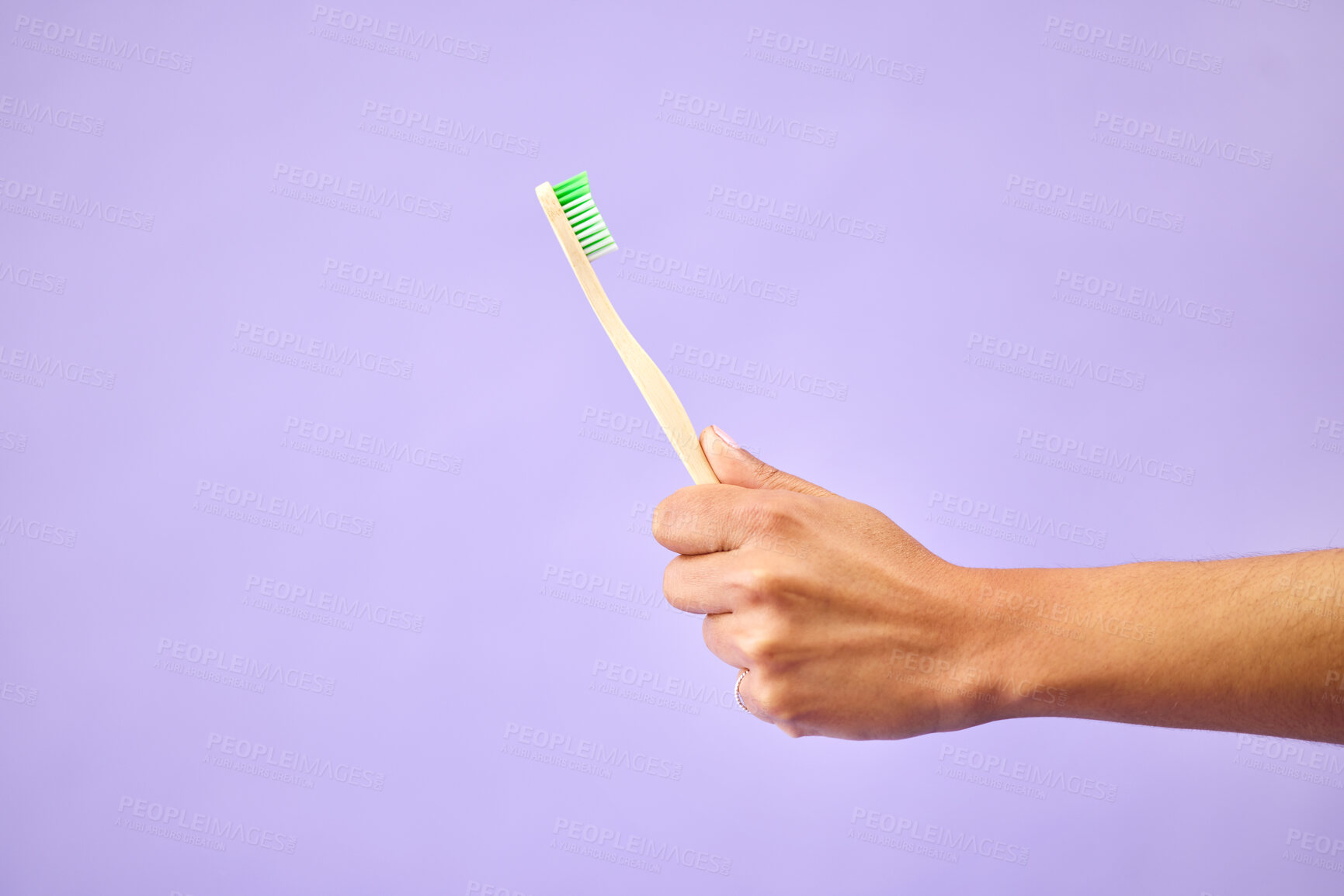 Buy stock photo Dental, teeth whitening and hand with toothbrush in studio for oral care, wellness and hygiene on purple background. Mouth, cleaning and person show bamboo tool for fresh breath, tooth or gum health