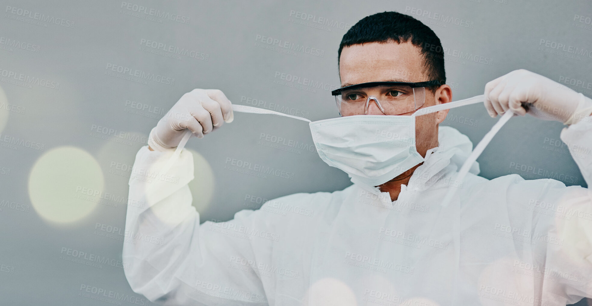 Buy stock photo PPE, face mask removal and man in safety suit of lab worker and healthcare professional in a hospital or clinic. Cleaning, bacteria protection for virus, pharmacy and wellness research with bokeh