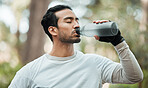 Sports, man and drinking water in park for exercise break, energy and workout rest. Thirsty athlete, asian runner and bottle for hydration, nutrition and healthy recovery of fitness in nature outdoor