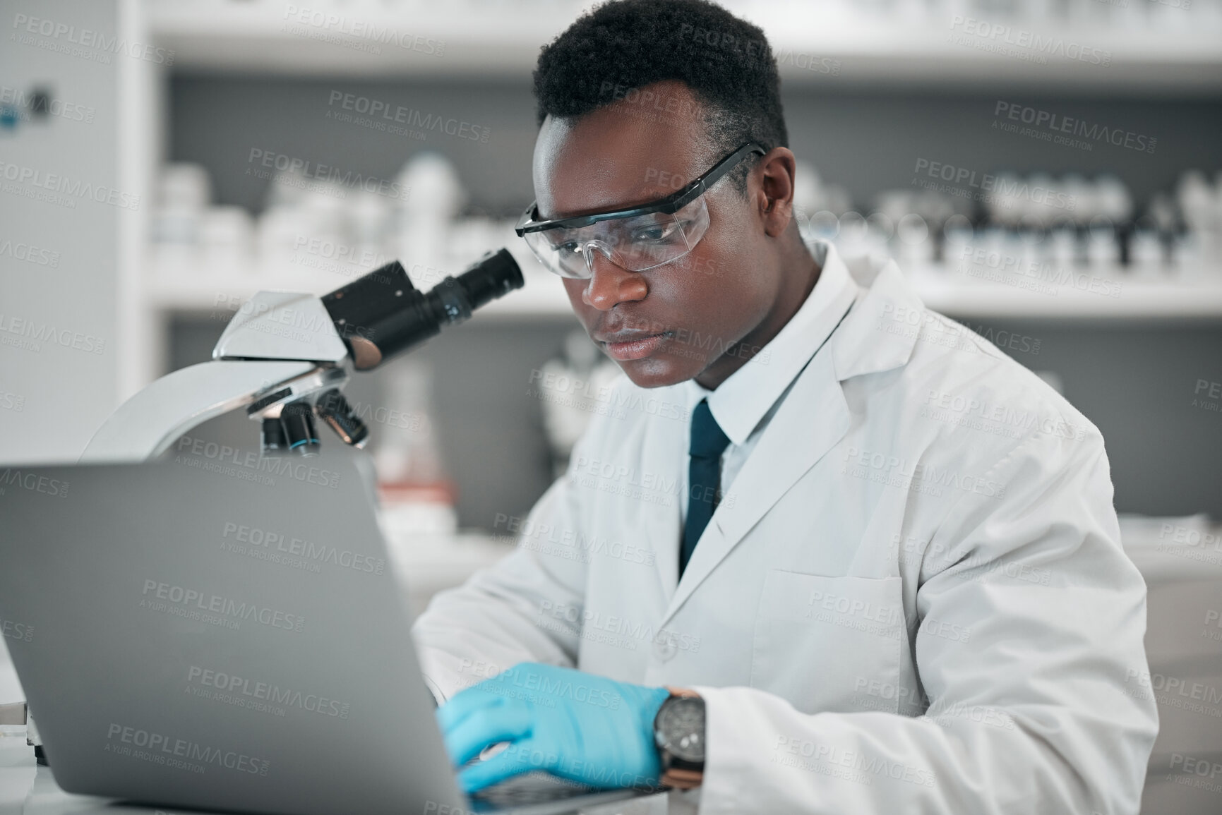 Buy stock photo Microscope, laptop and black man with research, medical and typing with data analytics, digital app and chemistry. African person, biologist or scientist with a computer, lab equipment and healthcare