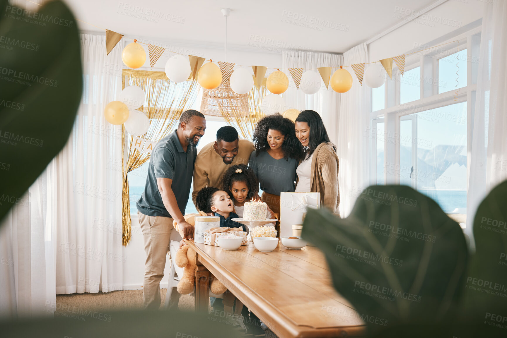 Buy stock photo Birthday, happy and family with child at a home for party, celebration or event together. Excited, decorations and kid blowing candles on cake with parents and grandparents in dining room of house.