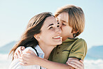 Family, mother and child kiss with blue sky on beach for love, happiness and vacation in mauritius by ocean. Nature, woman and kid by sea in summer for relax and adventure together with smile or joy