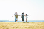 Running, parents and children on grass by ocean for bonding, relationship and relax together. Nature, travel and happy mother, father and kids on holiday, summer vacation and playing for freedom