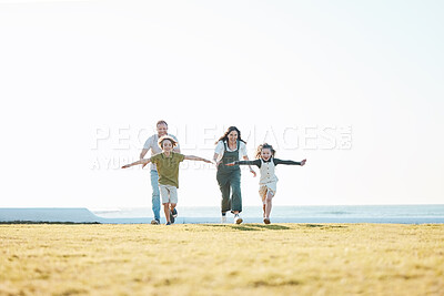 Buy stock photo Running, parents and children on grass by ocean for bonding, relationship and relax together. Nature, travel and happy mother, father and kids on holiday, summer vacation and playing for freedom