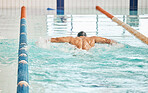Swimming pool water, sports and person doing stroke practice, cardio exercise or training for triathlon event. Energy performance challenge, athlete motivation and back of swimmer in competition race