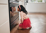 Child baker in kitchen, looking in oven and waiting for cookies, learning and home education. Girl checking baking, sitting on floor and excited for homemade treats, dessert and cooking for children.