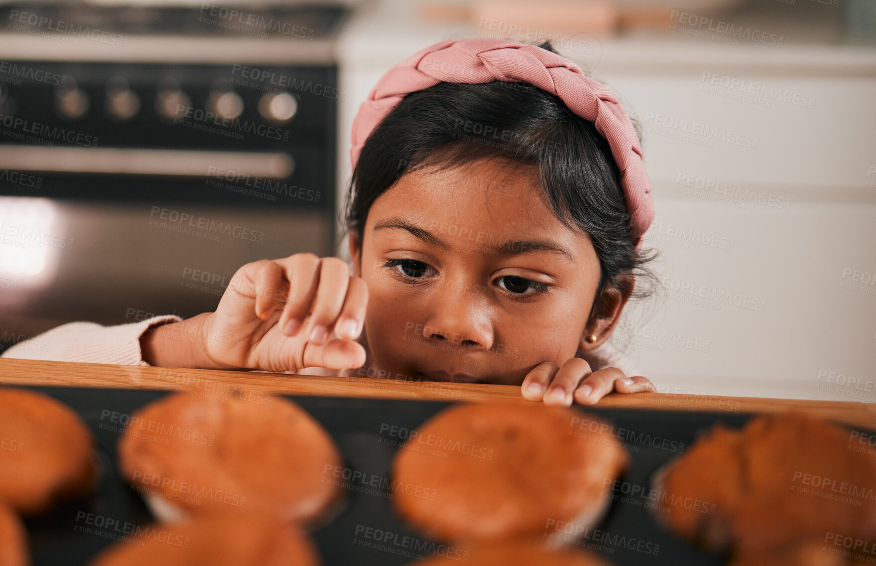 Buy stock photo Baking, muffin and a sneaky indian girl in the kitchen of her home to steal a fresh pastry from the counter. Food, children or cooking with a young kid looking naughty at a baked snack closeup