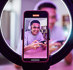 Influencer, man and gaming for social media or live streaming, gamer online with technology and phone screen. Ring light, streamer and closeup, filming video or content creation with broadcast