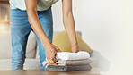 Towel, worker hands and living room with cleaning service in a home with fabric, cloth and material for washing. Laundry pile, person and cleaner with house maintenance, packing and housekeeping