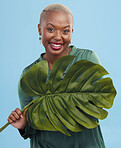 Black woman, monstera leaf and beauty, face with natural cosmetics and fashion on blue background. Silk green dress, eco friendly skincare and dermatology, African model glow and portrait in studio 