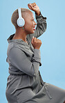 Black woman, headphones and dancing in studio profile, happy and listening by blue background. African dancer girl, smile and streaming subscription for sound, audio tech and hearing for celebration