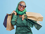 Shopping, sunglasses and black woman with bags, excited and boutique products on a blue studio background. African person, customer or model with luxury items, expensive clothes and rich with retail