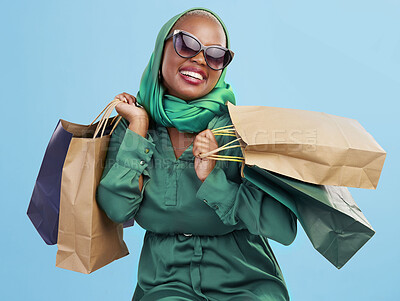 Buy stock photo Shopping, sunglasses and black woman with bags, excited and boutique products on a blue studio background. African person, customer or model with luxury items, expensive clothes and rich with retail