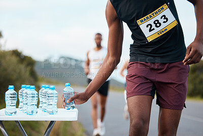 Hand, water and a marathon runner in a race or competition closeup for fitness or cardio on a street. Sports, exercise or running with an athlete grabbing a drink while outdoor on a road for training