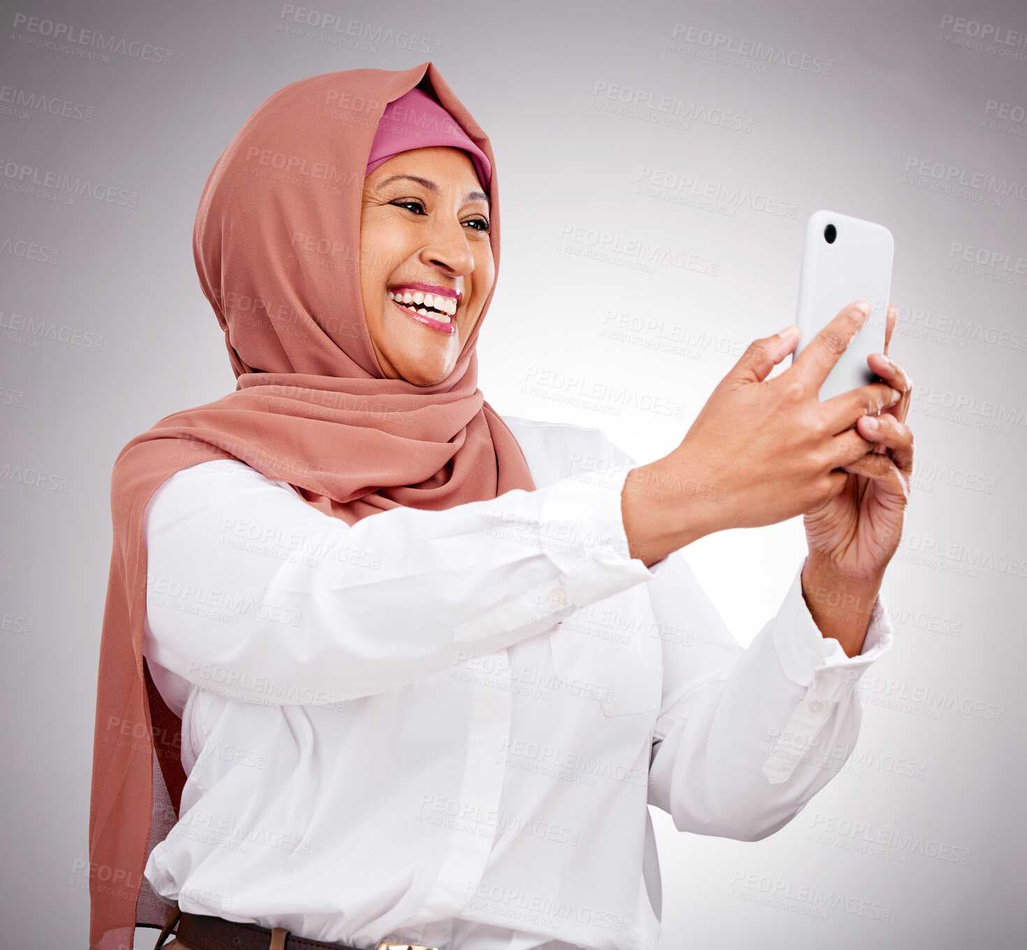 Buy stock photo Muslim woman, smile and selfie for social media, influencer content creation or fashion blog in studio. Happy islamic woman from Saudi Arabia with profile picture or photography on white background