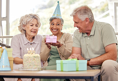 Buy stock photo Birthday, senior friends with cake and gift for celebration in living room, smile and candles in retirement. Happiness, old people and party with dessert, surprise and elderly man with women on sofa.