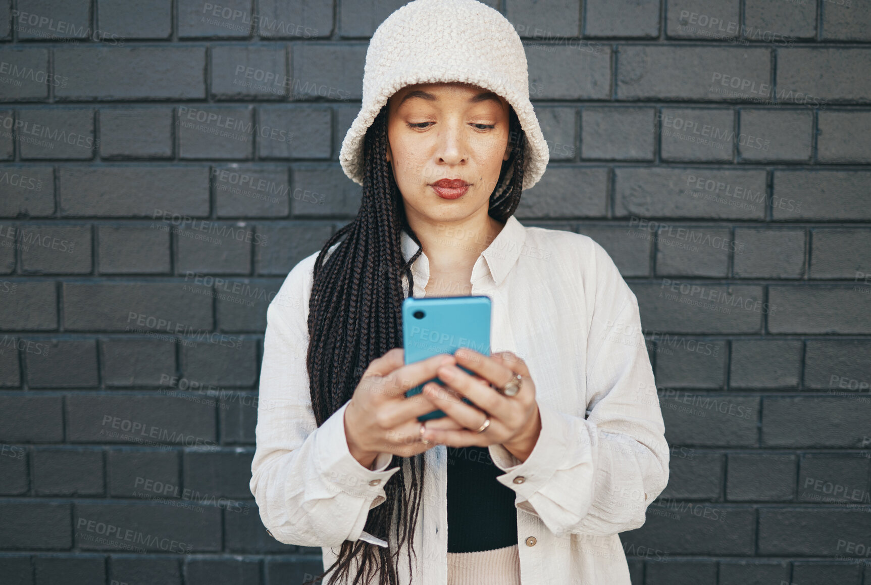 Buy stock photo Girl with phone, brick wall and urban fashion, typing social media post, chat or internet search. Streetwear, gen z girl or online influencer with smartphone for content creation and communication.