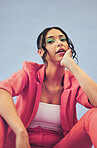 Business woman, makeup and portrait gen z style with fashion and sitting in studio. Trendy, stylish and female professional with model freedom, entrepreneur and modern clothes with blue background