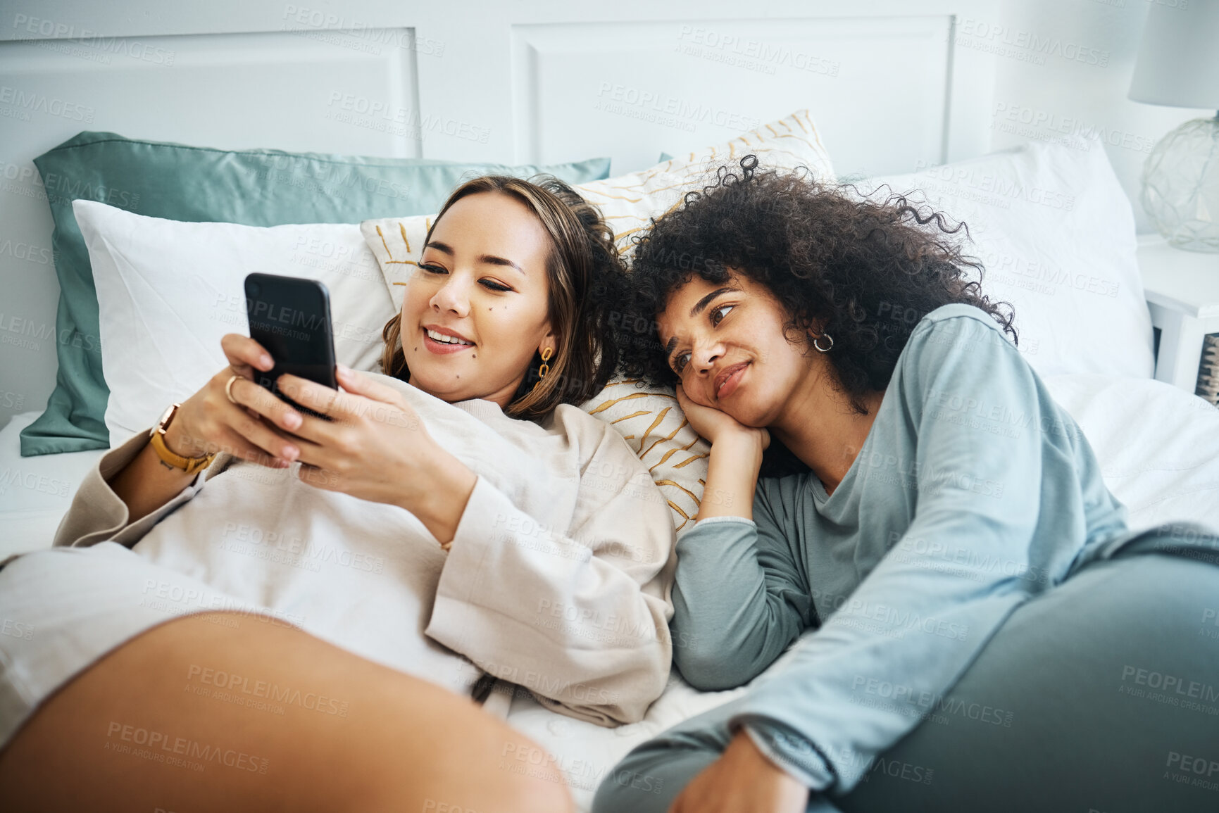 Buy stock photo Phone, love and a lesbian couple in bed together in the morning for communication or to relax. Social media, lgbt and a woman watching a movie or video with her girlfriend in the home bedroom