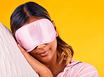 Peace, eye mask and woman sleeping in a studio with pillow for comfortable rest in pajamas. Calm, self care and young female model taking a nap, dreaming and relaxing isolated by yellow background.