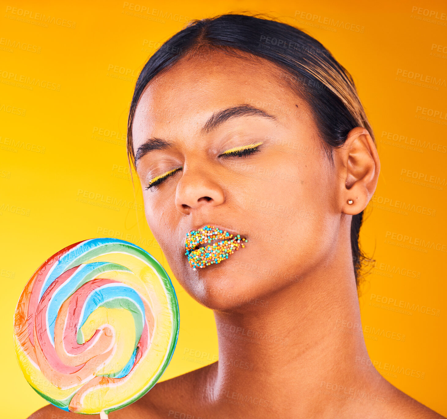 Buy stock photo Beauty, lollipop and woman with makeup, candy and sprinkles on her lips on yellow studio background. Person, girl or model with sweet treats, aesthetic and dessert with mockup space or colorful snack
