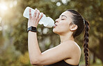 Woman, fitness and drinking water in nature for hydration, natural nutrition or sustainability. Thirsty female person with mineral drink or bottle in rest after workout, exercise or outdoor training