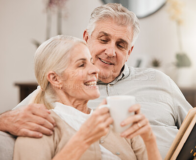 Buy stock photo Senior couple, coffee and reading book on a sofa with love, smile and retirement in a home. Elderly people, communication and lounge on a couch with study for knowledge in a house happy and relax 