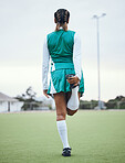 Back, legs and a woman hockey player stretching for the start of a game or competition outdoor. Sports, fitness and warm up with an athlete getting ready for a training workout or practice on a field