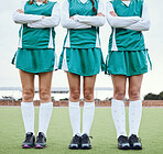 Legs, arms crossed and a woman hockey team outdoor on a field for a game or competition together in summer. Fitness, feet and sports people on a pitch of a grass for training or teamwork on match day