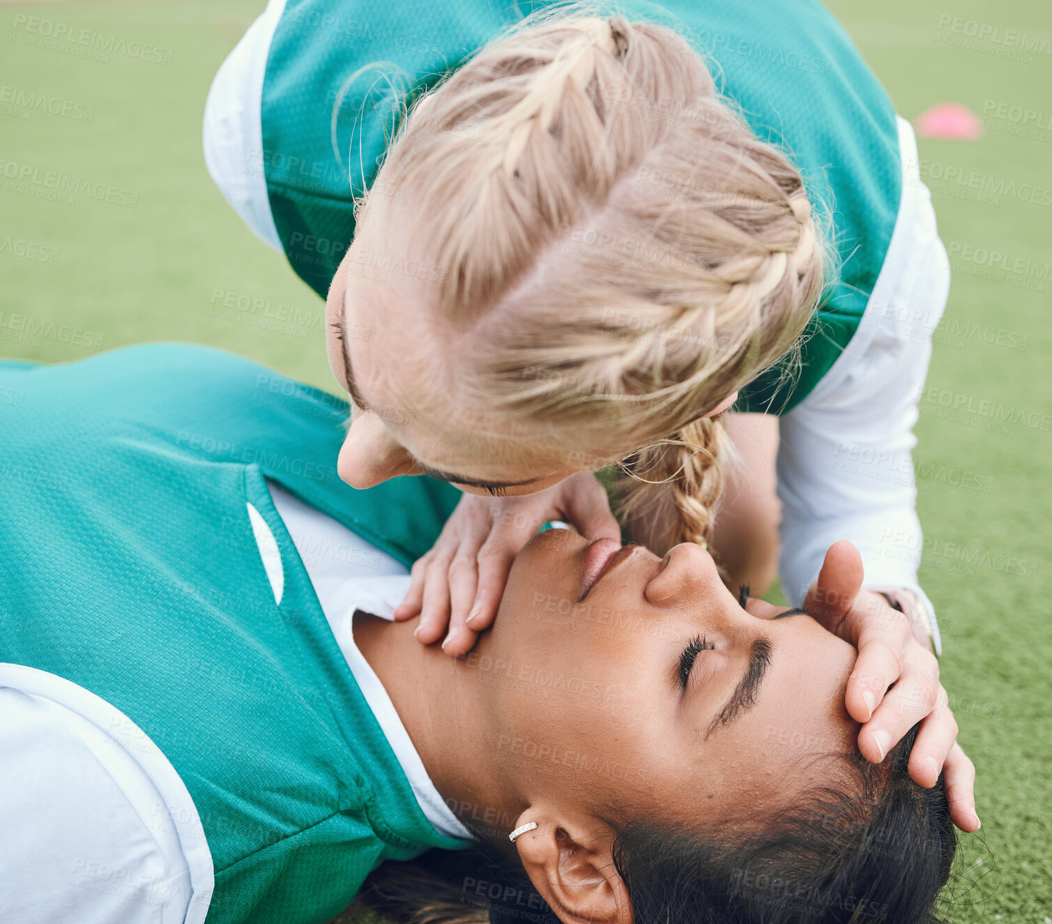 Buy stock photo First aid, breathing and emergency with a hockey player on a field to save a player on her team after an accident. Fitness, cpr and heart attack with a woman helping her friend on a field of grass