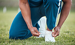 Person, tie and shoes on grass in fitness or getting ready for sports workout, training or outdoor exercise. Closeup of athlete tying shoe on field in preparation for running or practice in nature